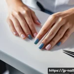 네일아트 실무에서 자주 발생하는 문제 해결법 - A close-up, high-angle shot of a female nail technician's hands, meticulously performing cuticle car...